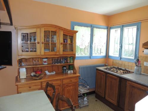 eine Küche mit Holzschränken, einem Herd und Fenstern in der Unterkunft villa ROSE GARDEN in Craponne-sur-Arzon