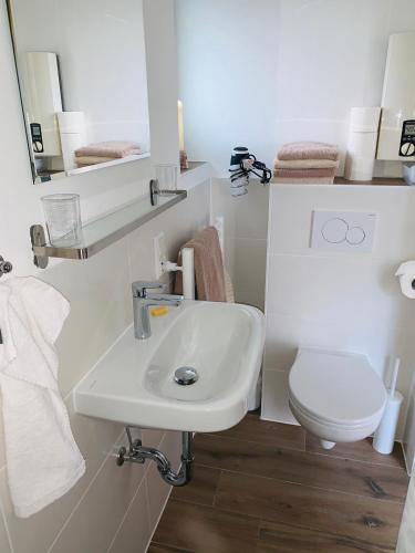 a white bathroom with a toilet and a sink at Haus Boy Jensen Wohnung Sonnenplatz in Wenningstedt
