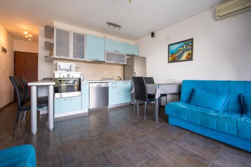 sala de estar con sofá azul y cocina en The Blue Apartments, en Budva