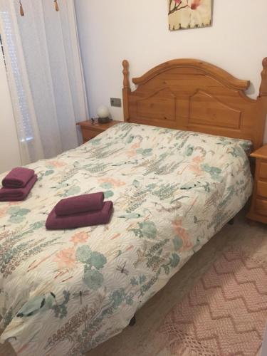 a bed with a floral bedspread and two towels on it at Sunny Breeze Apartment in Mojácar