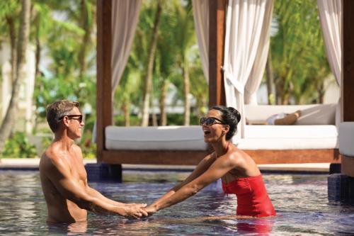 two people in the water in a swimming pool at Secrets La Romana All-Inclusive Adult Only Resort & Spa in Bayahibe