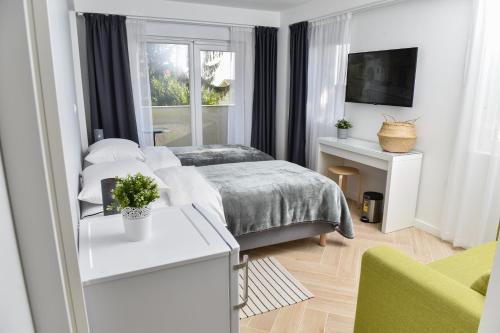 a white bedroom with a bed and a window at Rooms at Zajčeva 34 in Zagreb