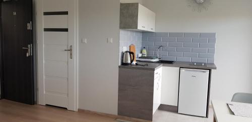 a kitchen with white cabinets and a gray tile wall at Apartamenty Maja -Pokoje - Domy wakacyjne -Basen Podgrzewany -Jacuzzi in Łeba