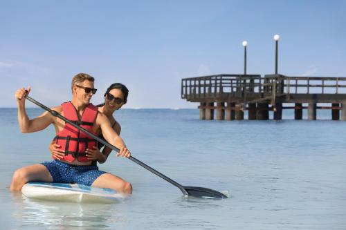 a man and woman on a paddle board in the water at Hilton La Romana All- Inclusive Adult Resort & Spa Punta Cana in Bayahibe