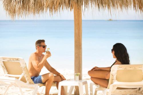 a man and a woman sitting in chairs on the beach at Secrets La Romana All-Inclusive Adult Only Resort & Spa in Bayahibe