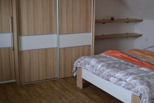 een slaapkamer met een bed en een aantal houten kasten bij apartmán 2+1 in Huštěnovice