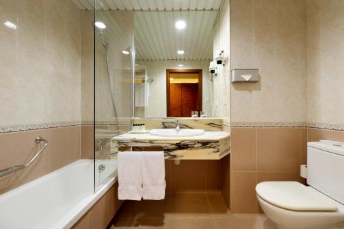 ein Badezimmer mit einem Waschbecken, einem WC und einem Spiegel in der Unterkunft Hesperia Sant Joan in Sant Joan Despí