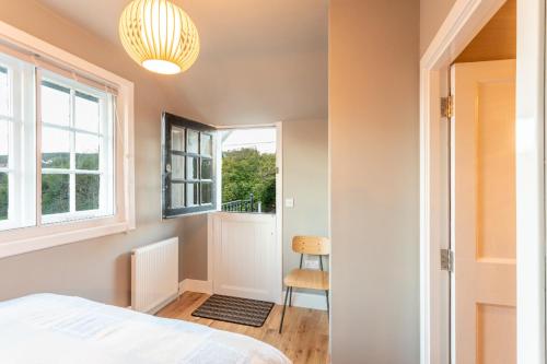 a bedroom with a bed and a window and a chair at Black Stair Cottage in Helensburgh