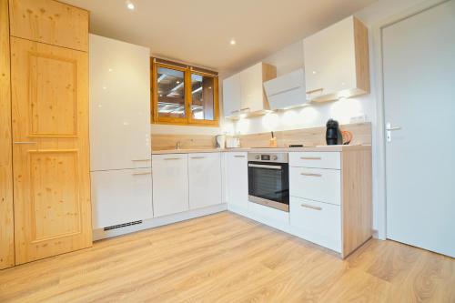 une cuisine avec des armoires blanches et un plancher en bois dans l'établissement lac Annecy - Talloires - situation exceptionnelle - calme et reposant, à Rovagny