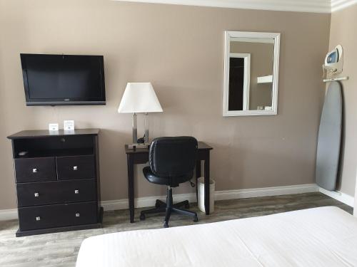 a bedroom with a desk and a chair and a television at Lotus of Lompoc - A Great Hospitality Inn in Lompoc