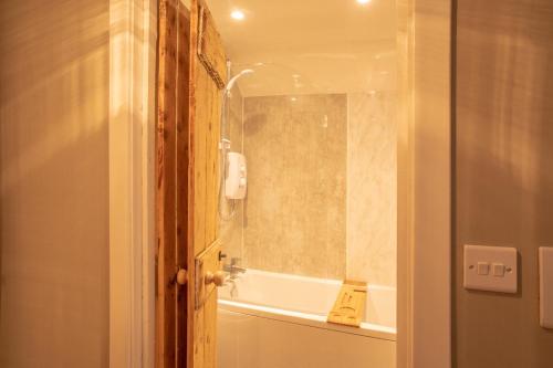 a bathroom with a shower and a tub and a sink at Black Stair Cottage in Helensburgh