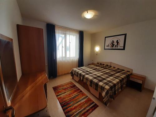 a bedroom with a bed and a window and a rug at Апартамент КАРЛИН in Pamporovo