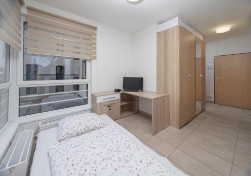 a bedroom with a bed and a desk and a window at Apartmán Berenika in Vrchlabí