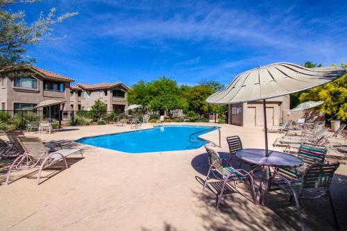 una mesa con sillas y una sombrilla junto a la piscina en Vistoso Condo #218C, en Oro Valley