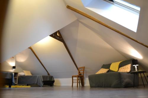 a room with a couch and chairs in a attic at Gîte Au Cœur de Cassel in Cassel