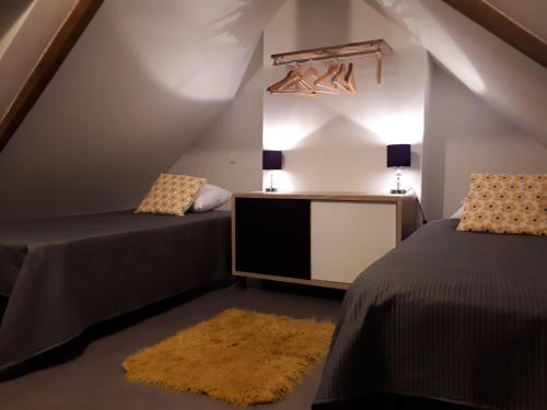 een slaapkamer op zolder met 2 bedden en een spiegel bij Gîte Au Cœur de Cassel in Cassel