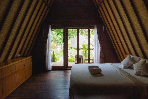 a bedroom with a bed and a large window at Batan Sabo Cottage in Nusa Penida