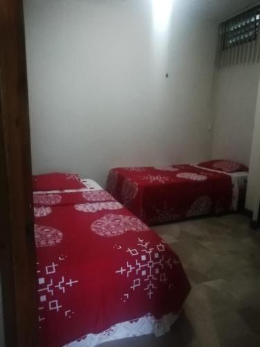 two beds in a room with red comforters on them at Departamentos 3 hab Manta - centro in Manta