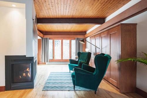 a living room with two green chairs and a fireplace at La Villa du Notaire in Lévis