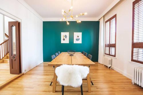 a dining room with a wooden table and a green wall at La Villa du Notaire in Lévis