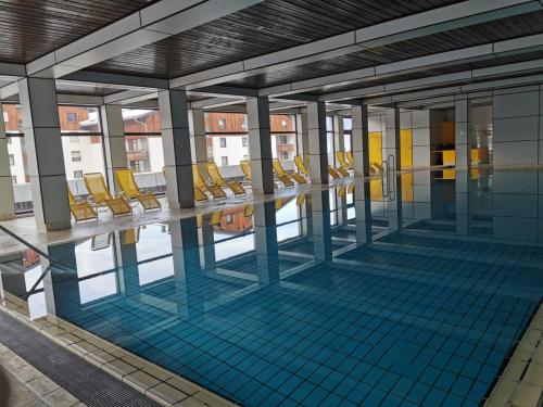 basen z żółtymi krzesłami w budynku w obiekcie Wohlfühl - Appartement Fewo Pichlarn Irdning Ferienwohnung w mieście Aigen im Ennstal
