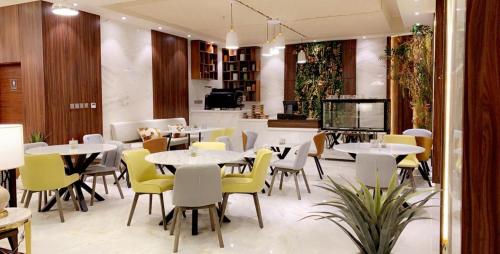 a restaurant with white tables and yellow chairs at mawasim al hay at hotel in Jeddah