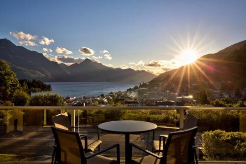 a table and chairs on a balcony with a view of a lake at Queenstown House Bed & Breakfast and Apartments in Queenstown