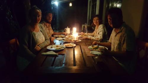 a group of people sitting around a wooden table with food at Rankaty Residence in Unawatuna