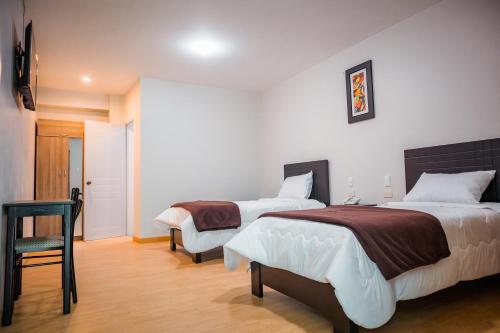 a bedroom with two beds and a chair at Hotel Puñuykuna - Cajamarca in Cajamarca