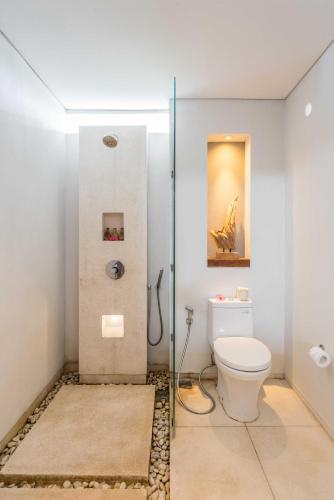 a bathroom with a toilet and a glass shower at Svarga Resort Lombok in Senggigi 