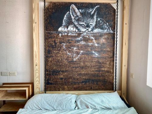 a painting of a cat on a wall above a bed at Shadow house in Tainan