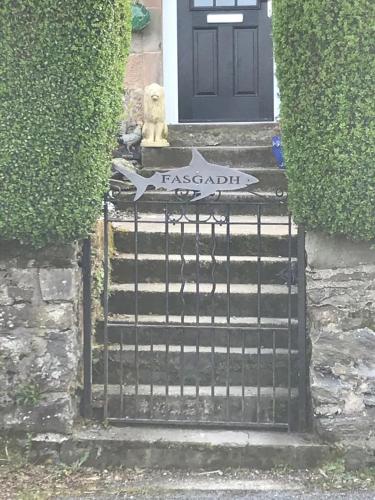 a dog sitting on a gate in front of a door at Fasgadh Rooms in Tarbert