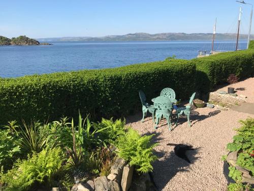 a table and chairs sitting next to the water at Fasgadh Rooms in Tarbert