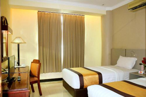 a hotel room with two beds and a desk at Pandanaran Hotel in Semarang