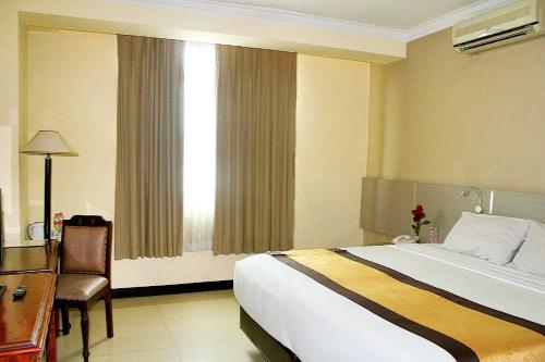 a hotel room with a bed and a desk and a window at Pandanaran Hotel in Semarang