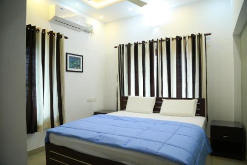 a bedroom with a bed with a blue comforter at DOWN TOWN HOLIDAYS in Trivandrum