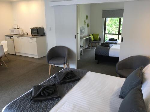 a hotel room with a bed and a desk and chairs at Half Moon Bay Motel in Auckland