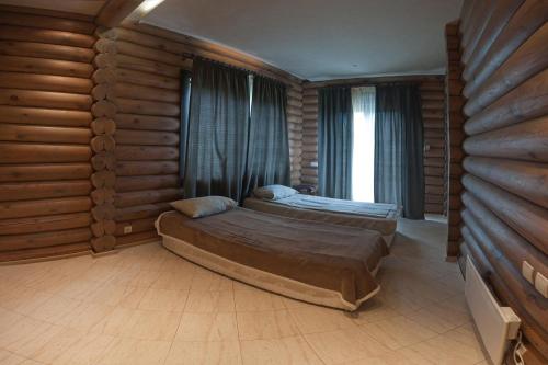 a bedroom with two beds in a room with wooden walls at Pastoral wooden hauses in Velikiy Les