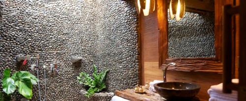 a bathroom with a stone wall with a sink at Puri Dajuma Beach Eco-Resort & Spa in Pulukan