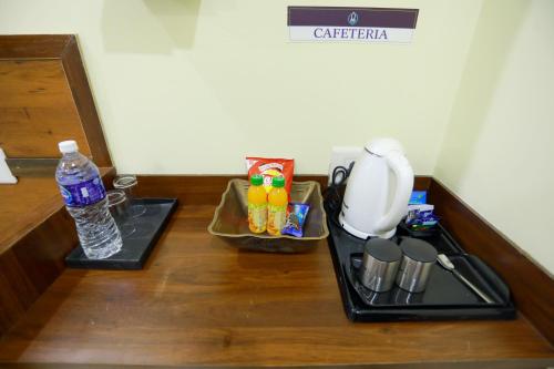 a counter with a coffee maker and a bottle of water at Base9 Cochin Airport Hotel in Nedumbassery