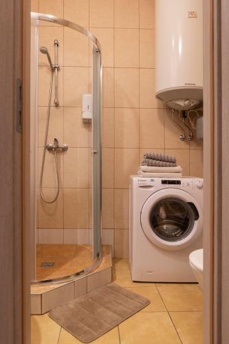 a bathroom with a washing machine and a shower at Sweet Apartments in Šiauliai