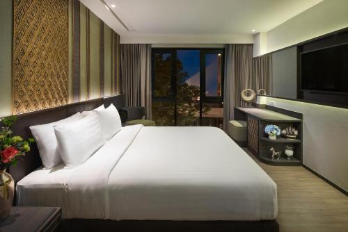 a bedroom with a large white bed and a television at Chillax Heritage Hotel Khaosan - SHA Extra Plus in Bangkok