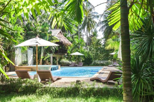 a swimming pool with lounge chairs and an umbrella at Long Beach Chalet - SHA Extra Plus in Ko Lanta