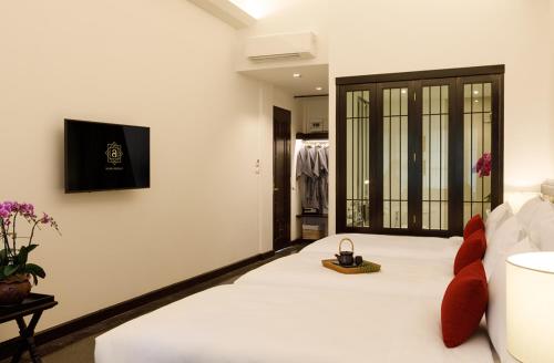 Un dormitorio con una cama blanca con reloj. en Aksara Heritage -SHA Extra Plus, en Chiang Mai
