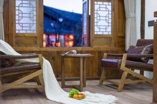 a room with two chairs and a table with fruit on the floor at Artistic-Suite in Lijiang