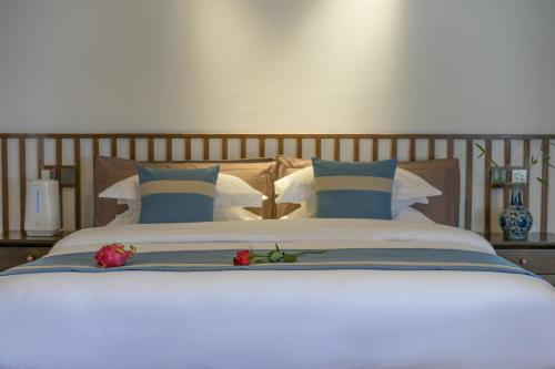 a bed with blue and white pillows and flowers on it at Artistic-Suite in Lijiang