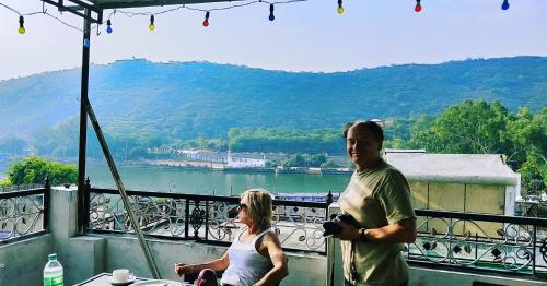 een man en een vrouw op een balkon met uitzicht op een meer bij Shivam Tourist Guest House in Būndi