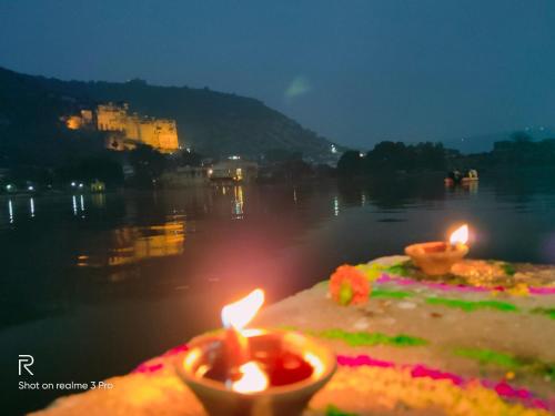 a cake with two candles on the shore of a body of water at Shivam Tourist Guest House in Būndi
