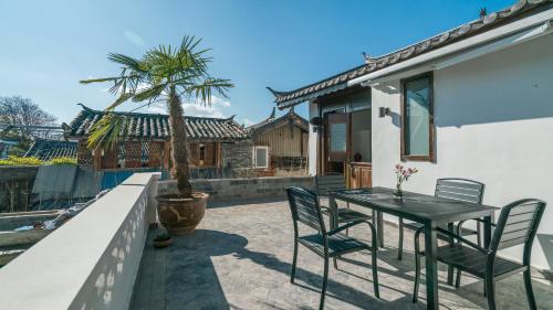 a patio with a table and chairs and a palm tree at Artistic-Suite in Lijiang