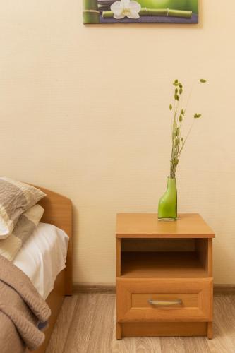 a table with a green vase on top of a bed at Pigi nakvyne in Šiauliai